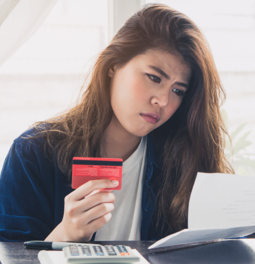 A woman holding her credit card looking at a statement