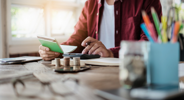 A man balancing a checkbook with stacks of coins in front of him