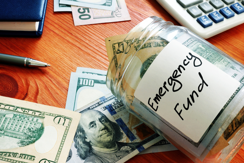 a jar labeled emergency fund sitting on a table to illustrate how much you should having in savings