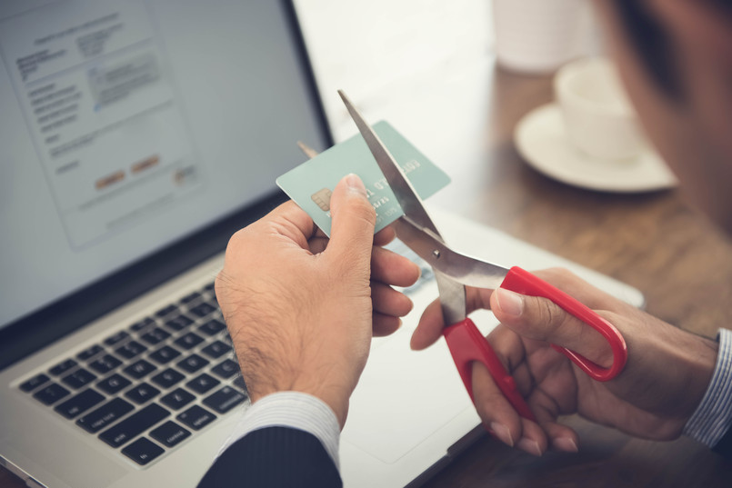 a man learning the how to cancel a credit card and cutting it to pieces with scissors