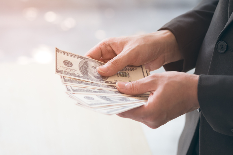 a man with a handful of 100 dollar bills he pulled out of an ATM from his credit card cash advance