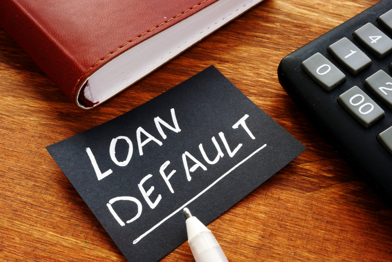 Person with calculator and book learning about their default on a loan