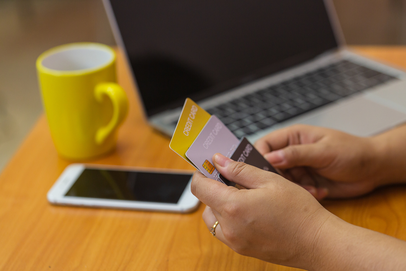 A woman holding multiple credit cards trying to decide how many credit cards should she have