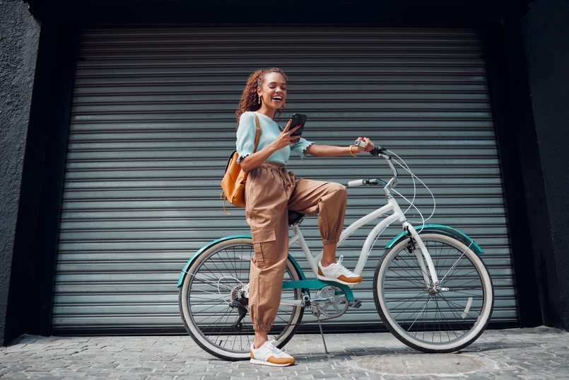 a young woman standing in front a bicycle looking at her phone