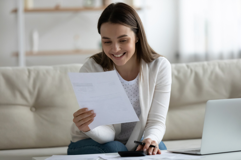  a woman who is financially literal, is reviewing her bank statement and deciding what to do with her extra money