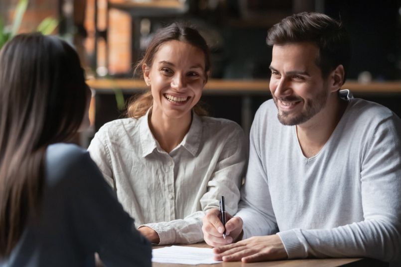 Joyful young couple considering personal loan cosigning. They're smiling, evaluating financial options, and discussing loan agreements.