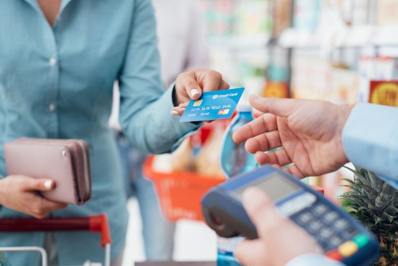 woman using a credit card to pay a transaction with the preconceived idea of how do credit cards work