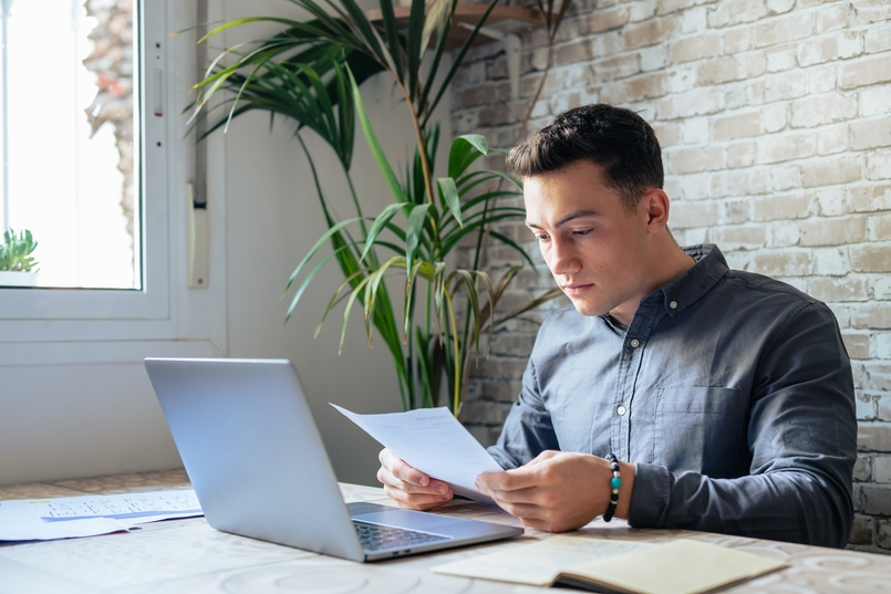 a young man, who recently learned how to read a credit report, is reviewing his credit report for accuracy