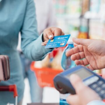Woman handing a credit card to a retailer to pay for goods