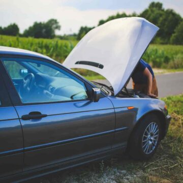 person looking at broken down car